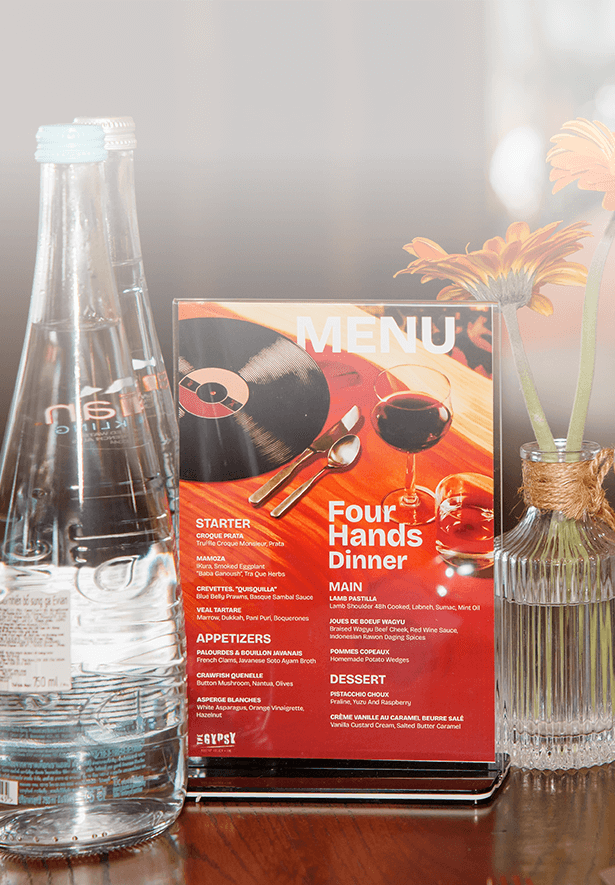 Table with "4 Hands Dining" Menu Card on table with evian® bottles. Table with "4 Hands Dining" Menu Card on table with evian® bottles.